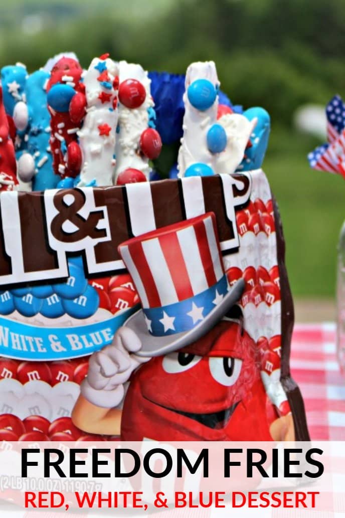 Red, white, and blue dessert for Memorial Day or Fourth of July. Pretzel rods covered in melted red, white, and blue chocolates with candy stick to them, displayed in an M&M's bag.