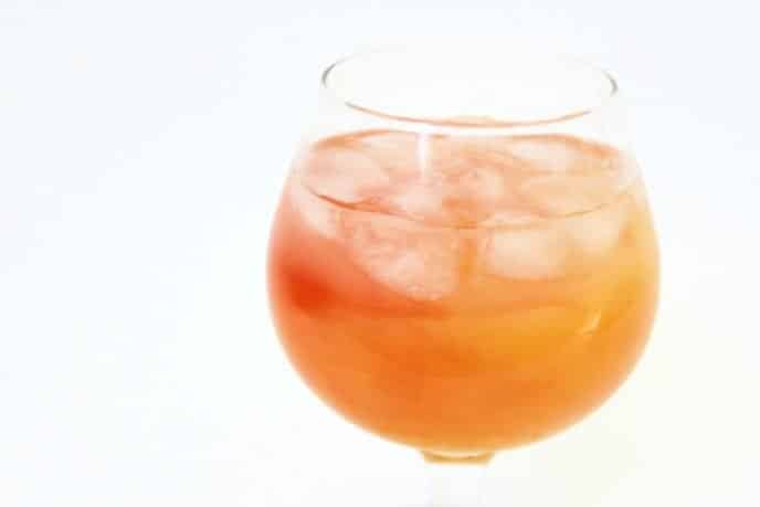 The Best Cocktails to Try This Holiday Lemonade cocktail recipe made with juices, in a glass with ice, white background
