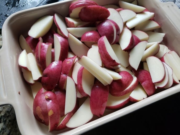 Red potatoes cut into pieces and placed into a casserole dish to get roasted.