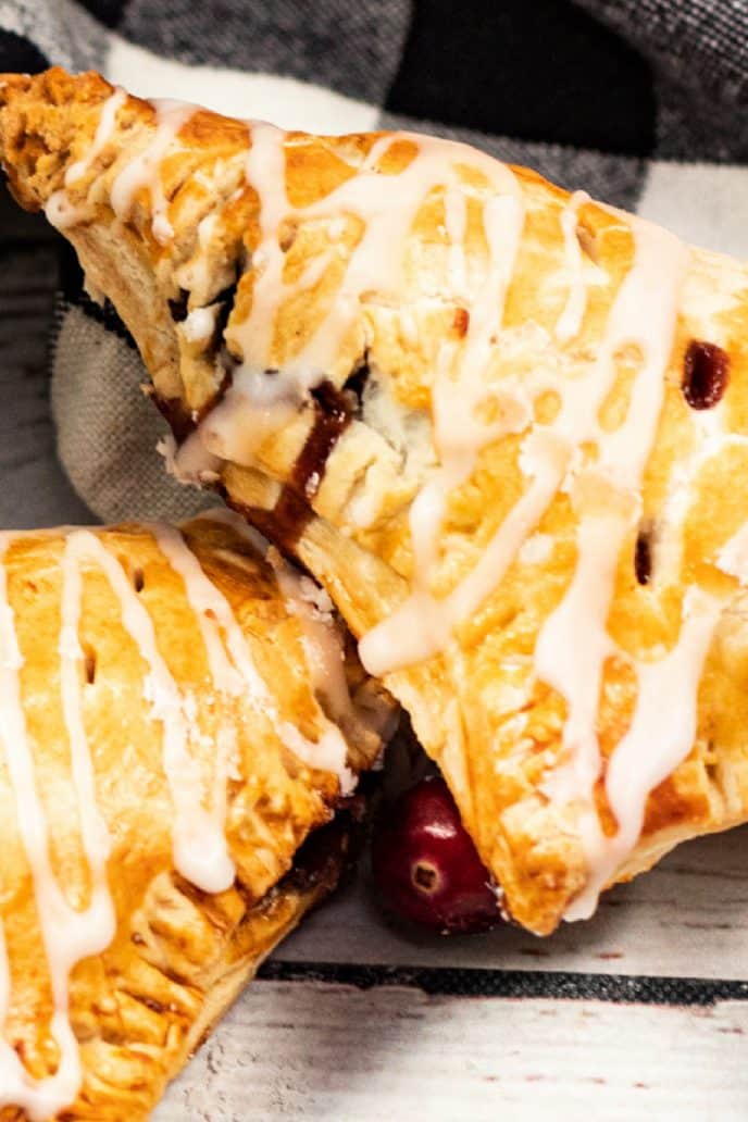 Apple turnovers with cranberry apple filling, baked golden brown and drizzled with icing.