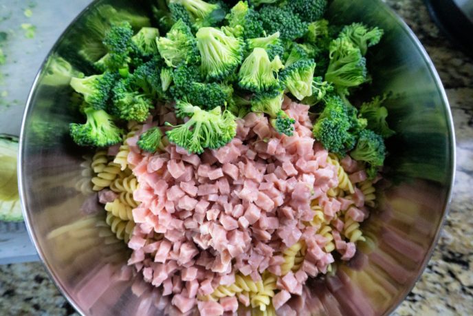 Pasta Salad Rotini, ham, and broccoli in a mixing bowl.