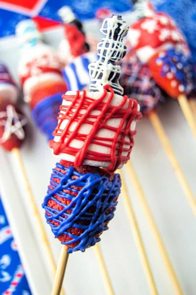 Easy 4th of July Dessert Strawberry, marshmallow, and blueberry dessert kabobs drizzled in patriotic red, white, and blue frosting for 4th of July dessert.