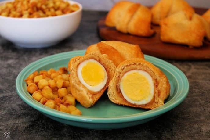 Crescent roll breakfast sandwiches with egg, ham, and cheese wrapped in a butter and flaky golden brown crescent roll, served with home fries