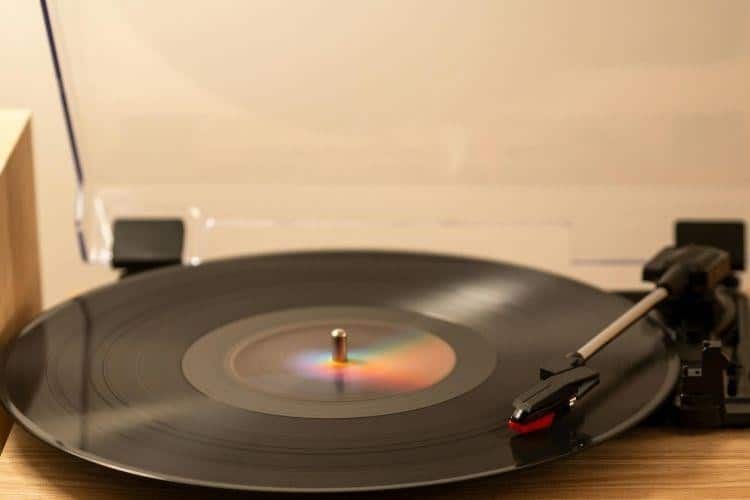 Vinyl record spinning on a wooden turntable with the tonearm nearby.
